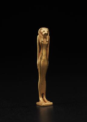 A gold, standing amulet of the goddess Bastet with her arms at her sides.