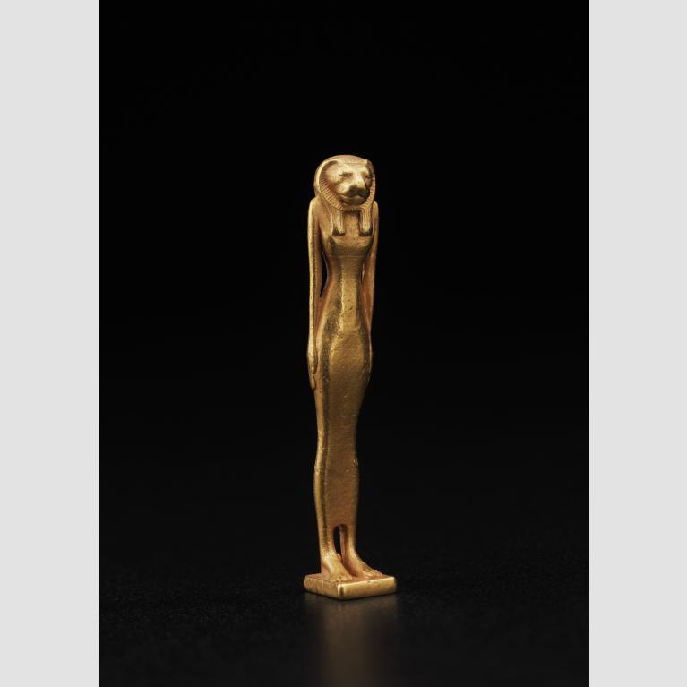 A gold, standing amulet of the goddess Bastet with her arms at her sides.
