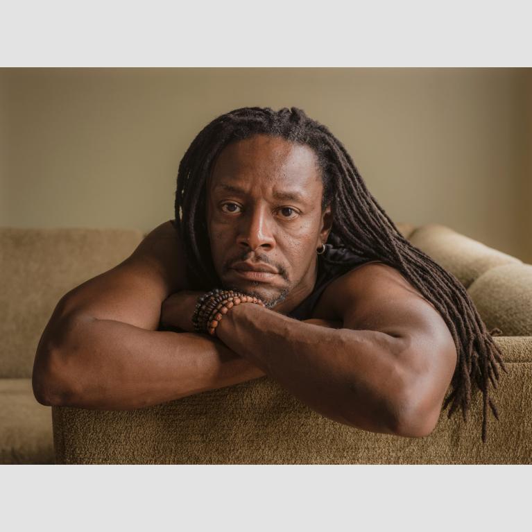 A photo of a man, Herb, lying on a couch resting his head on his crossed arms. 