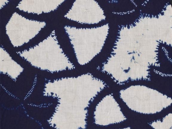 A detail of white woven cotton dyed with a dark blue pattern.
