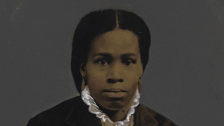 An African American woman in a dark overcoat poses for a photo.