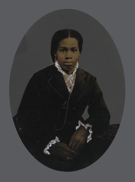 An African American woman in a dark overcoat poses for a photo.