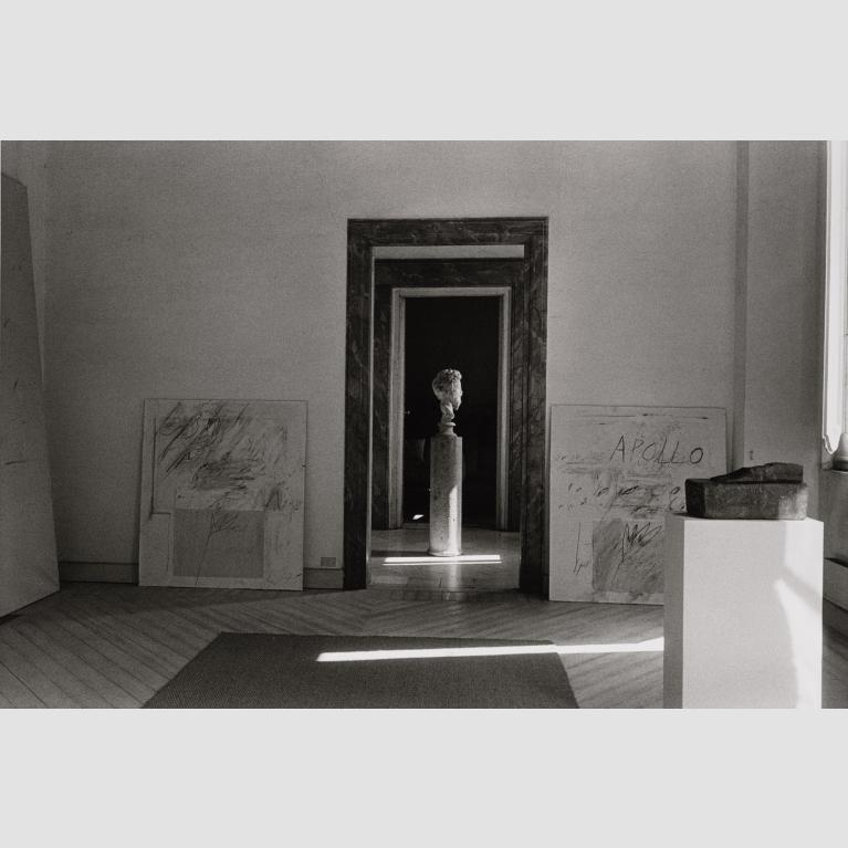 A bust on a pedestal seen through a door frame.
