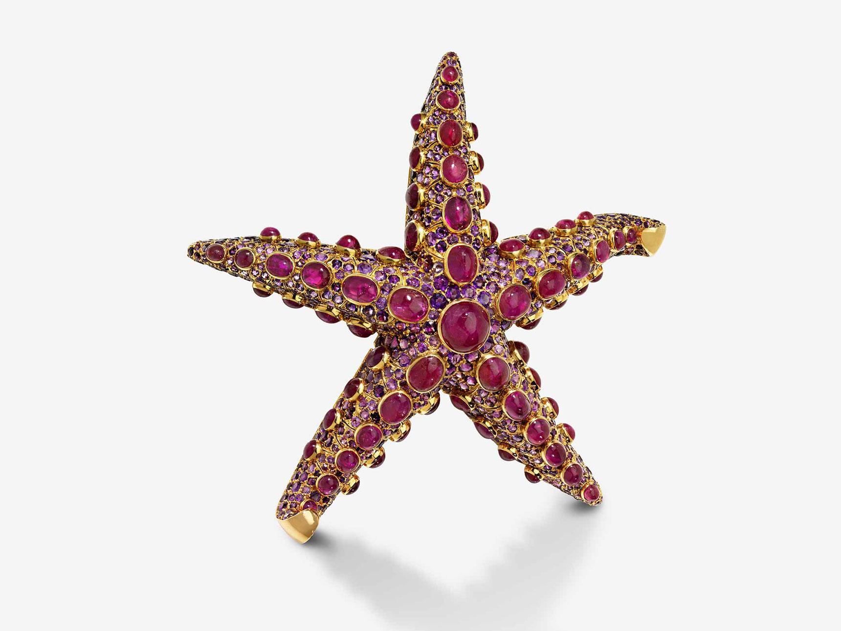 A gold brooch in the shape of a starfish with many purple gems on it