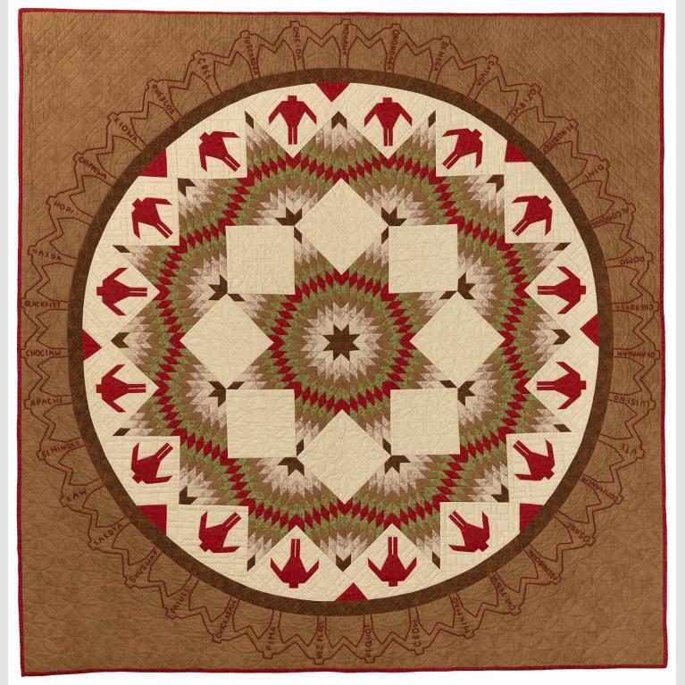 Quilt of browns, reds, and whites with a circle with figures and star shaped patterns