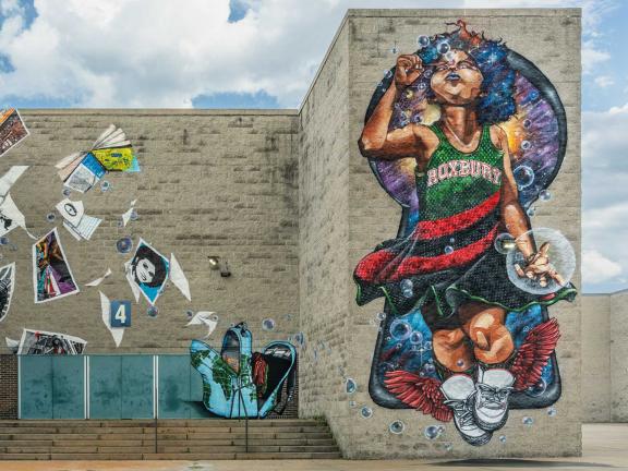 large mural depicting little girl blowing bubbles surrounded by books