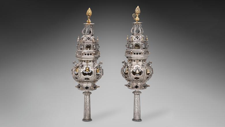 A pair of ornate Torah finials standing up against a gray background.