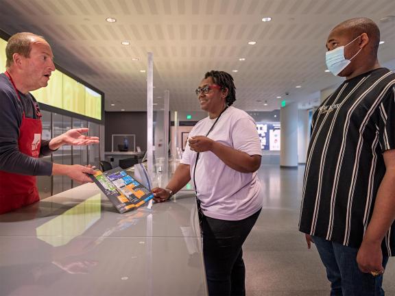 Museum staff giving two visitors directions in Sharf Visitor Center