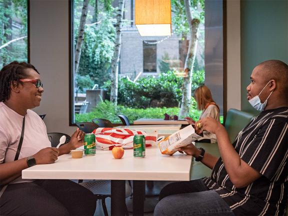 Two visitors sitting and eating food at a table in the Museum's cafeteria