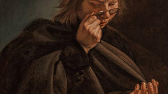 A young boy holds glasses up to his face to read a book.