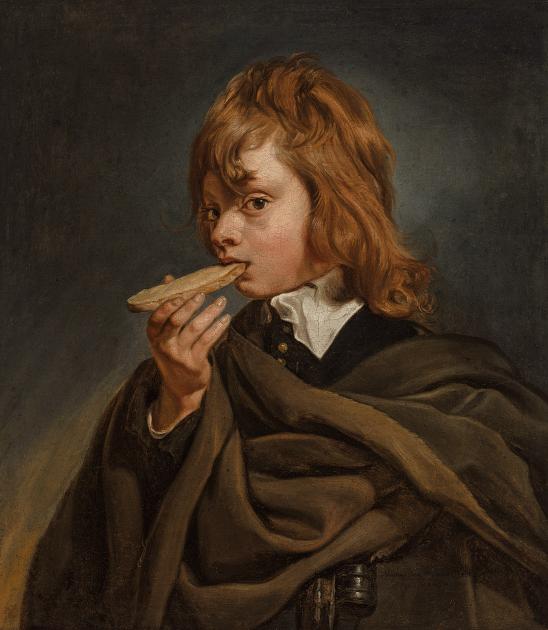 A young boy eats a piece of bread.