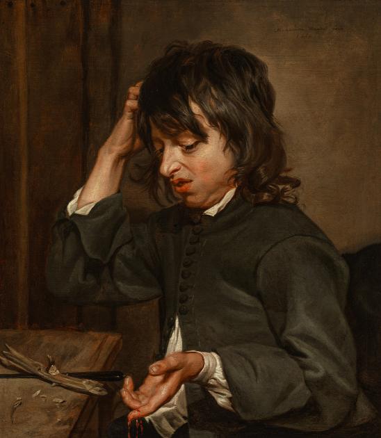 A young boy looks down disgustedly at his right hand, which is covered with dirt.