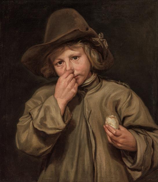 A boy wearing a hat pinches his nose with his right hand.
