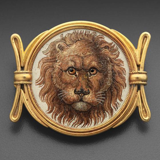 A micromosaic brooch painted with the head of lion and surrounded by a gold frame.