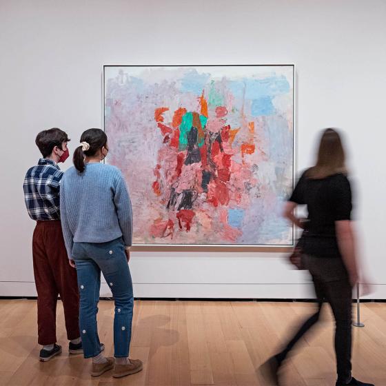 Visitors looking at Guston paintings hanging on gallery wall