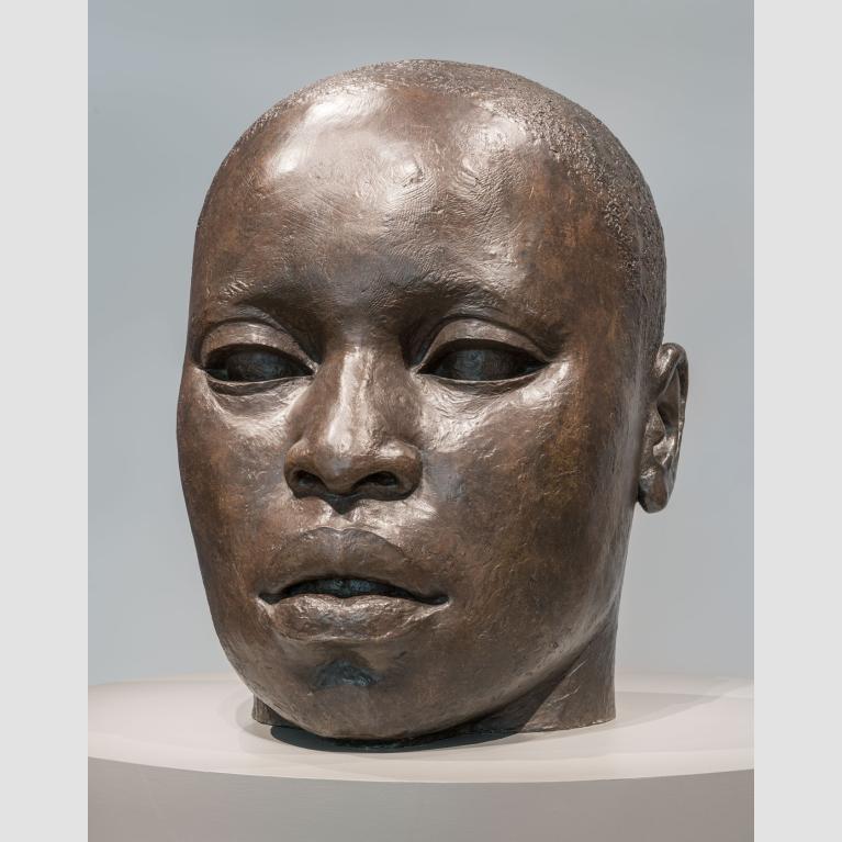 A large, bronze sculpture of the head of an African American man.