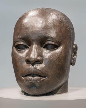 A large, bronze sculpture of the head of an African American man.
