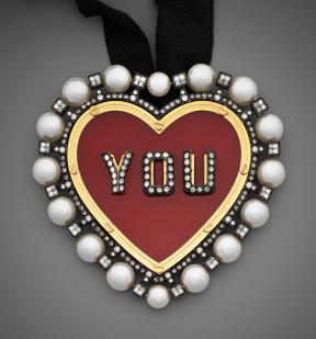 A heart-shaped necklace with the word "You" in the center. 