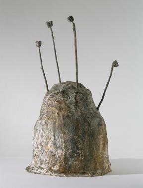 A bronze sculpture in the shape of a mound with four rods sticking out of the top. 