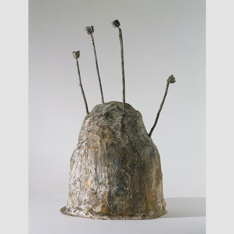 A bronze sculpture in the shape of a mound with four rods sticking out of the top. 