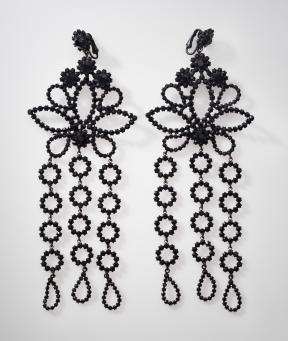 A pair of black glass earrings with a floral design and three dangling pieces. 