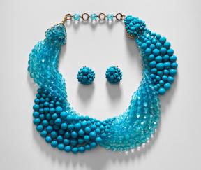A pair of turquoise glass earrings sit inside a matching beaded necklace. 
