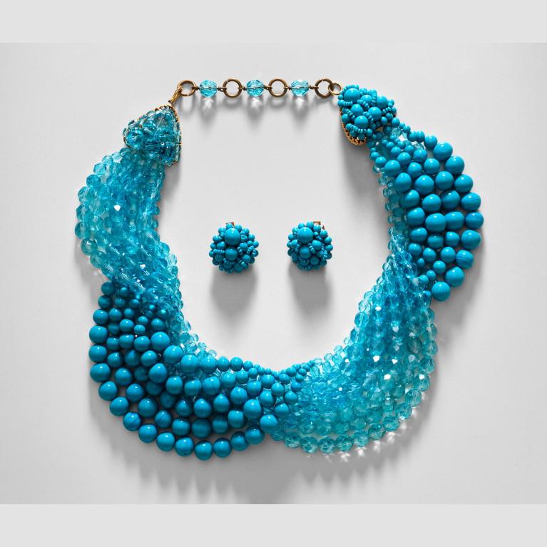 A pair of turquoise glass earrings sit inside a matching beaded necklace. 