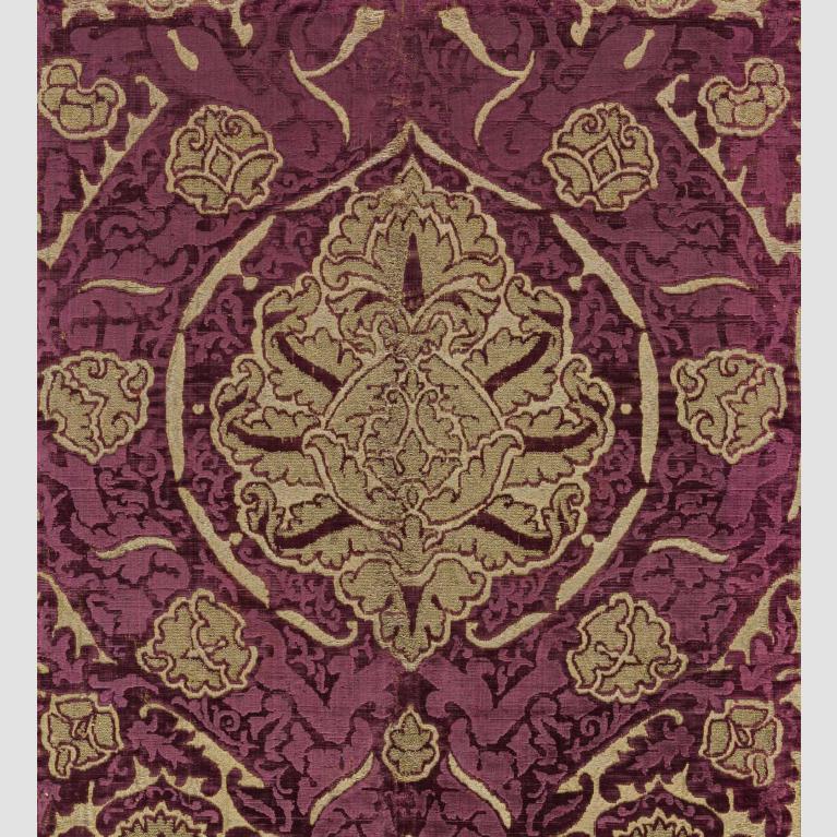 A piece of deep red velvet adorned with a gold velvet design. 