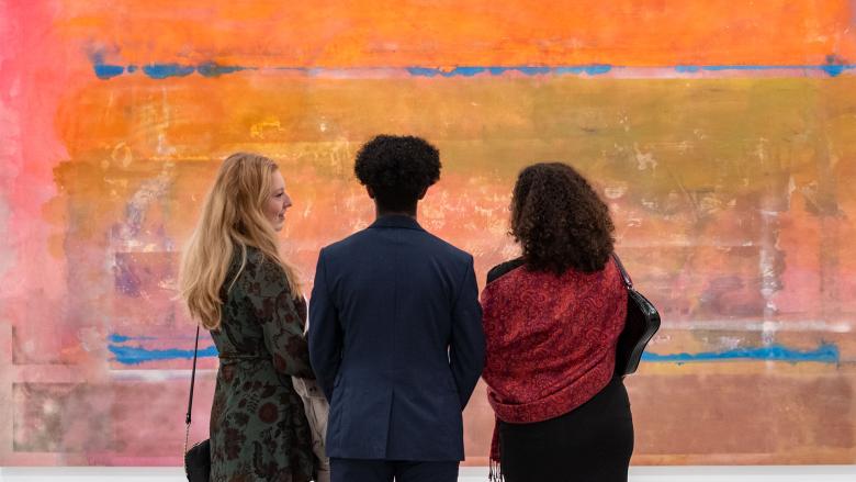 Three visitors view a painting in the Frank Bowling's Americas exhibition.