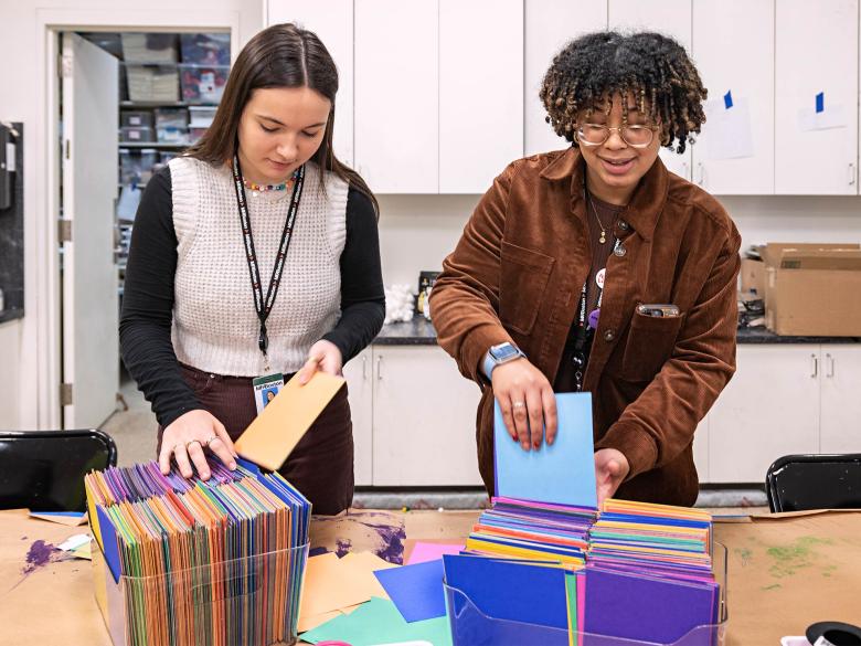 Two MFA Pathways Interns file colorful folders