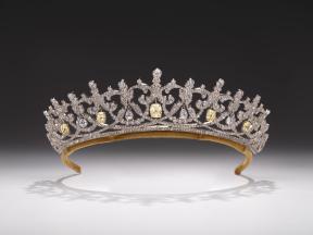 An ornate tiara made of silver and clear Swarovsky crystals with touches of yellow .