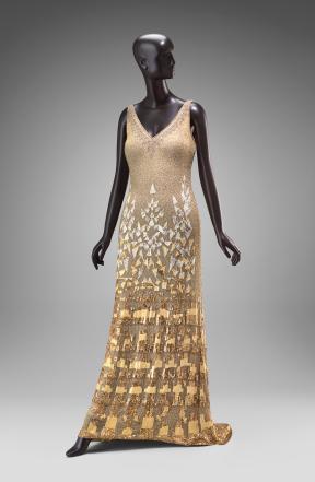 A mannequin wears a silk gold embellished dress. 