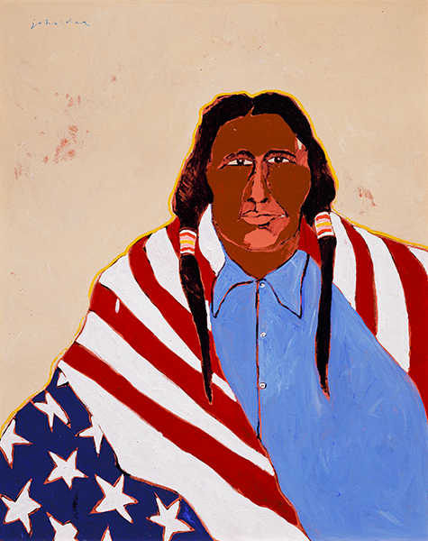 A Native American man in a blue button-down shirt stares straight forward with an upside-down American flag draped over his shoulders.
