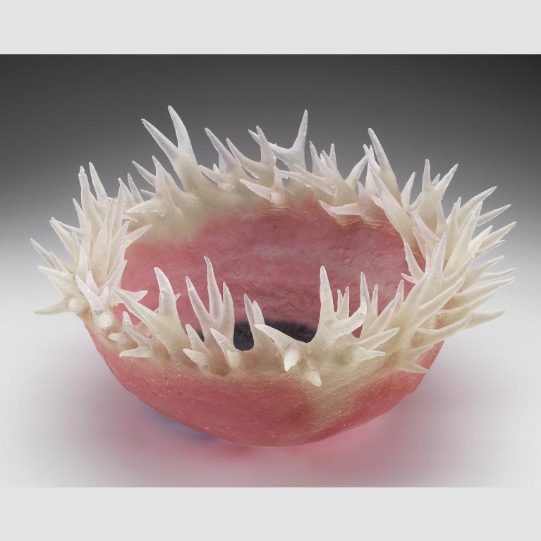 A pink glass bowl with translucent thorn-like tendrils surrounding its ridge.
