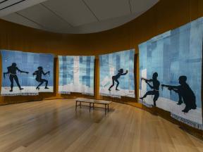 A four-panel tapestry of five silhouetted figures pulling on a rope or a chain. 