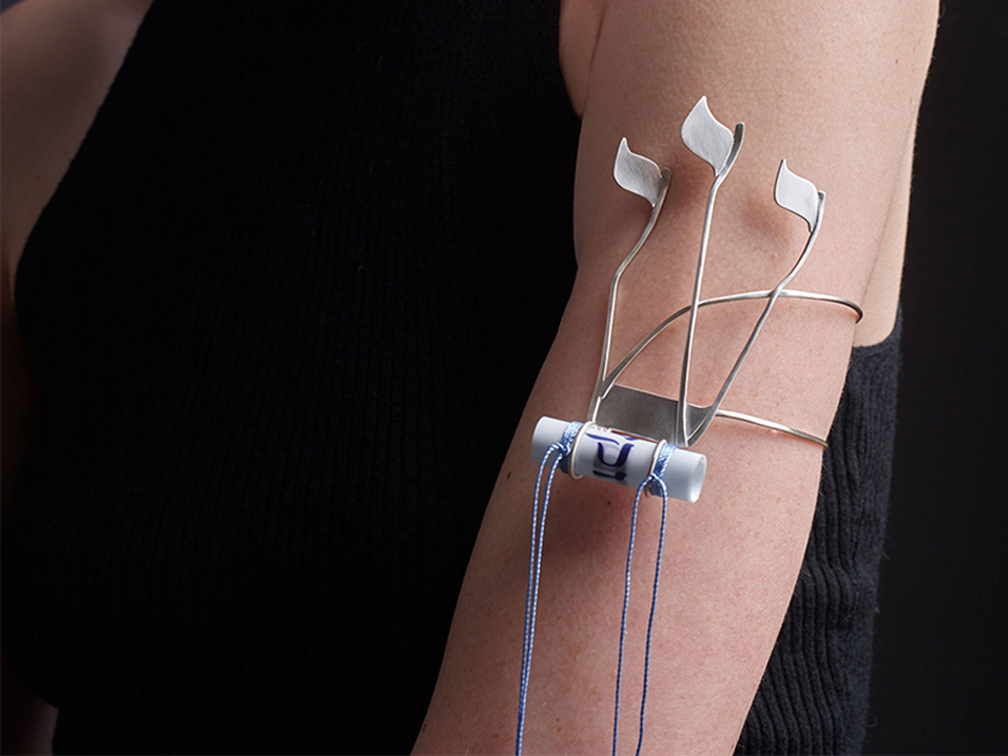 A woman's arm adorns a silver bracelet with Hebrew letters