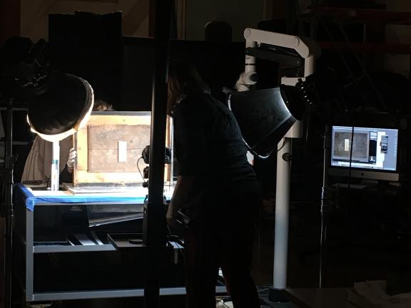 Conservators examining inscriptions on the base of a sculpture